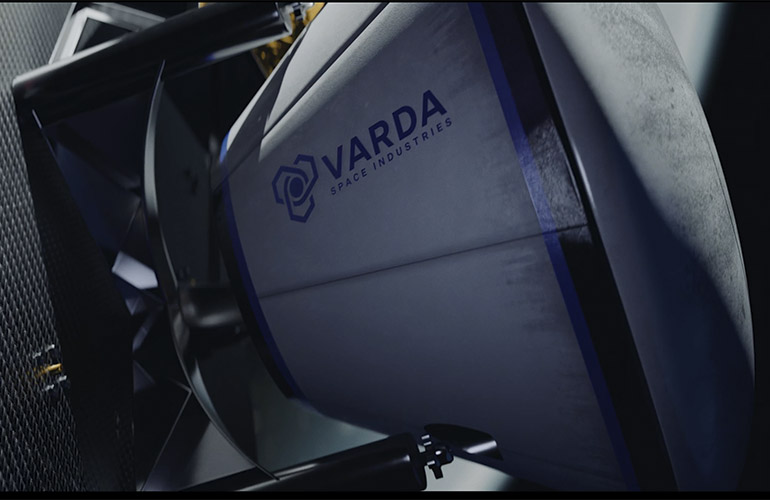 This is a screenshot from a Varda Space Industries promotional video showing a space capsule with the company's logo docking onto a satellite.