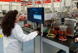 A bench-scale upstream setup at Thermo Fisher's Bioprocess Design Center, with a glass bioreactor of amber cell-culture media alongside a row of Thermo Scientific HyPerforma single-use bioreactors and peristaltic pump arrays. (Credit: Thermo Fisher Scientific)